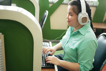 Disability young blind person happy woman in headphone typing on computer keyboard working in...
