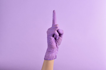 A woman's hand in a medical rubber lilac glove shows or points up at something on an isolated...
