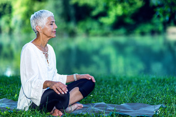Senior woman meditating by the water