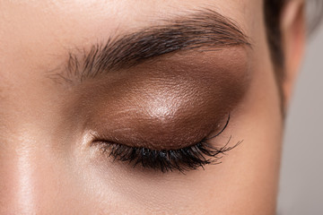 Female closed eye close-up. Eye makeup for eyebrows and eyelashes. Brown shade nude