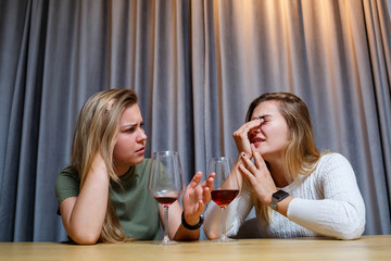 A woman consoles a sad depressed friend who needs help. Depression with alcohol concept. upset young girl with unhappy face holding a glass of wine looking at her best sister