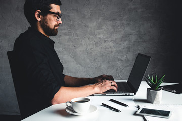 A man sits with a laptop in a black shirt. Business concept, work. Office routine. Property efforts