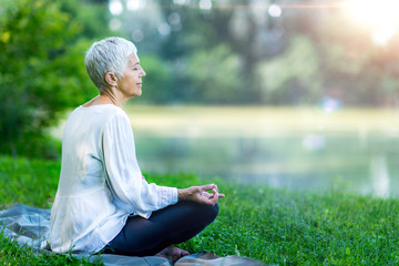 Senior woman meditating by the water
