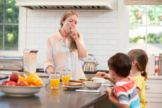 Mom who is feeling under the weather with kids in kitchen, struggling to get the kids breakfast and ready to start the day 