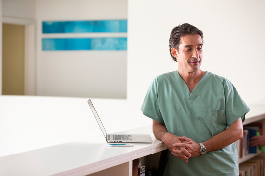 Portrait of Hispanic Male doctor in his home taking a break from practicing Tele-medicine, looking off camera 