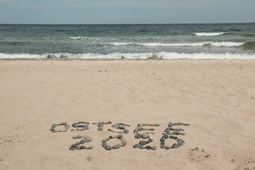 Schriftzug Ostsee 2020 am Strand mit schwarzen Steinen