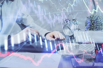 Double exposure of man's hands holding and using a phone and financial graph drawing. Analysis concept.