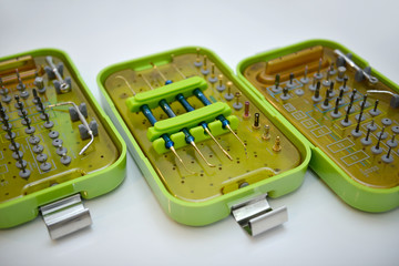 dental instruments with different attachments in gold and silver colors are placed in green boxes with brown lids