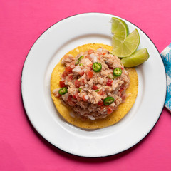 Canned tuna ceviche with chili pepper and tomato on pink background