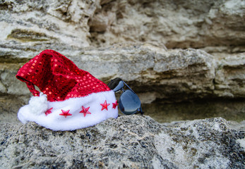 Happy New Year holidays and Merry Christmas at Sea. christmas hat lying on the rocks