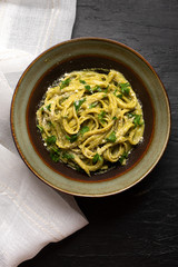 Creamy green pasta with poblano pepper and parmesan cheese on dark background