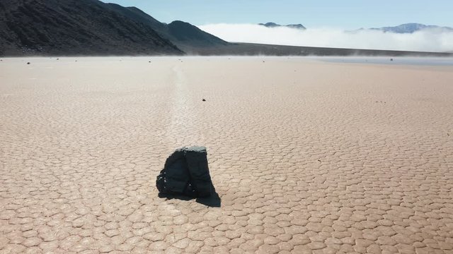 Famous race track playa with moving rocks by the dry cracked surface of Death Valley desert, California, USA. Cinematic 4K aerial around the famous moving rocks in the Death Valley on sunny morning.