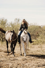 Woman riding bareback on horse shows farm and ranch lifestyle with horses close up ponying through...