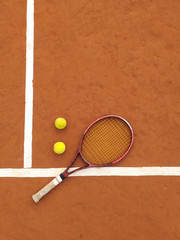 Raqueta y dos pelotas de tenis en una cancha de tenis de polvo de ladrillos