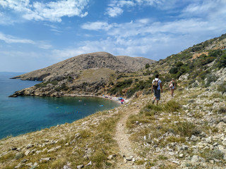 male and female young tourist walking towards Oprna bay in Stara Baska, island Krk, Croatia