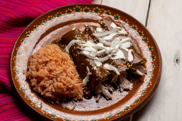 Mexican chicken enchiladas with mole sauce and rice on white background