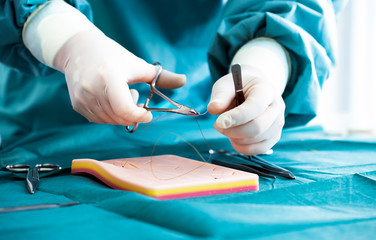 Doctor teaches the technique of suturing and closure on silicone pad. Doctor teaching and suturing practice in basic skills on skin silicone pad. Simple interrupted suture. Vertical mattress suture.