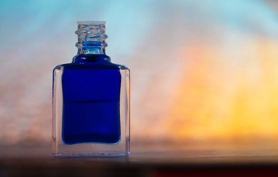 A bottle of aurasoma with a blue essence against an abstract background.