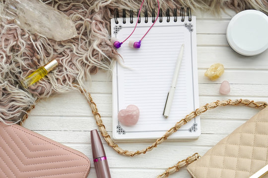 Women's flatlay with notebook, handbag, cosmetics, cristall and minerals.