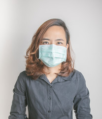 Close up face shot of pretty asian woman model with age of 30s who is wearing medical mask to protect virus and influenza epidemic shows strong and beauty eye contact on white background in studio