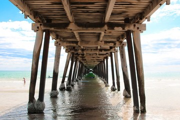 One-point perspective shot taken underneath a wooden jetty, or pier, on a beach in South Australia.