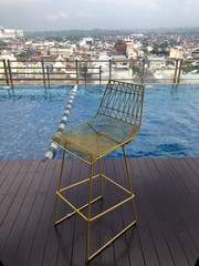 minimalist iron chair beside the swimming pool, with a view of the city building.