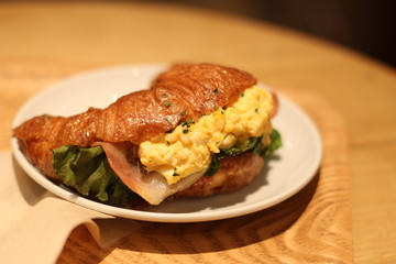 Close up of a delicious ham and egg salad croissant bread sandwiches on a white plate, Kagoshima, Kyushu, Japan, soft focus 
