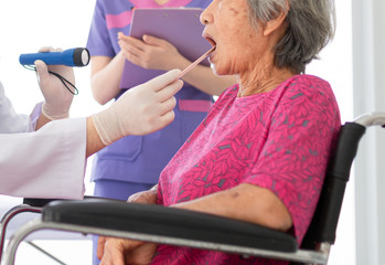 doctor use tongue depressor with old patient, he screening and diagnosis, elderly health check up