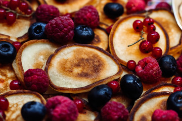 Mini pancakes with fresh summer berries food background close up.