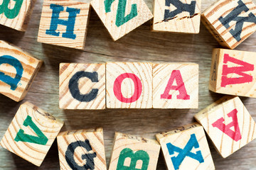 Alphabet letter block in word COA (abbreviation of certificate of analysis, certificate of authenticity, cause of action) with another on wood background