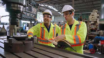 Group of factory workers using machine equipment in factory workshop . Industry and engineering concept .