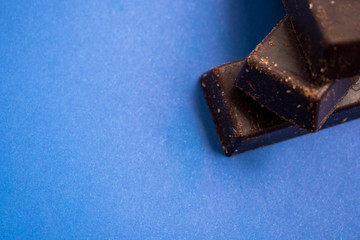 Fresh and sweet chocolate bars on a blue surface 