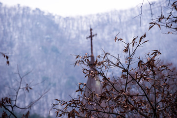 The religious cathedral church tower in the forest background snowy mountain.