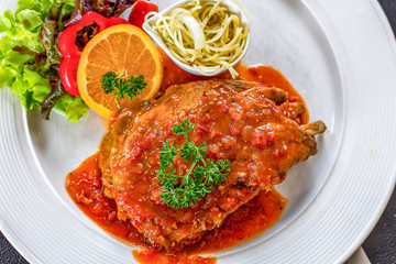 Pork ribs, vegetables and spaghetti in a white dish topped with sauce