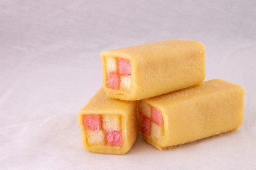 Delicious mini Battenberg cake, the tradional sweet afternoon tea snack. Pink and yellow sponge cake covered in jam wrapped in almond marzipan.