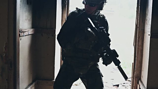 Armed soldier entering hallway of abandoned building, checking rooms.