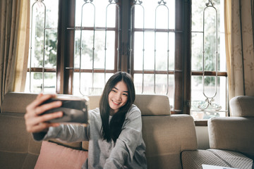 Young adult asian woman selfie photo by mobile phone at home