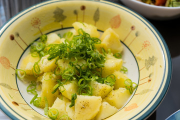 Cooked potatoes with finely chopped green onions on top of the plate