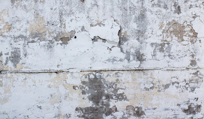 wall texture with old white plaster that has cracked and fallen off