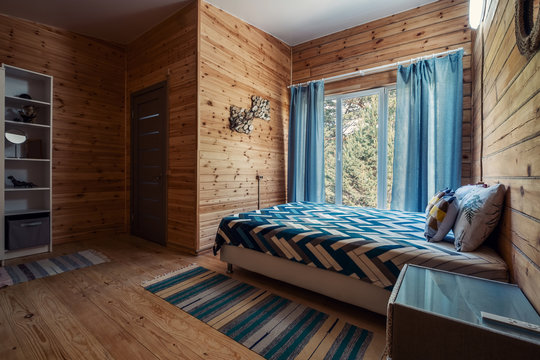 Wooden bedroom interior in mountain summer resort. Big windows, open doors