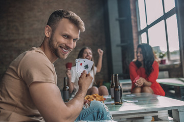 Smiling man cheating with an ace card while playing cards