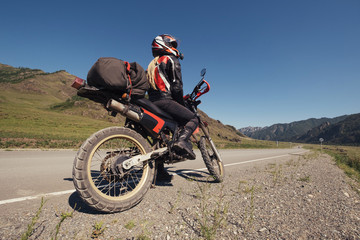 Fototapeta na wymiar Woman traveling by enduro motorcycle in mountains road