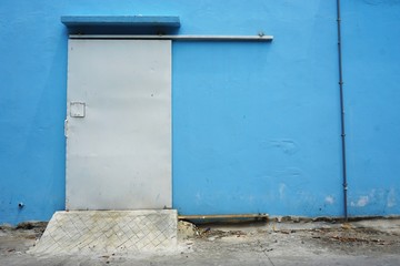 Sliding metal door set in a blue painted wall in urban Southeast Asia