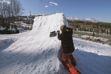 snowboarder male  build quarter pipe snowboard outdoor near ski resort in mountains. Sunny winter...