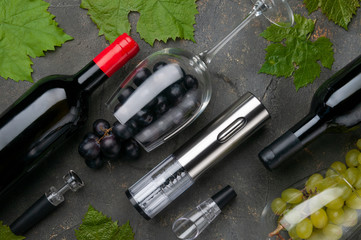 Electric metal corkscrew, wine aerator and vacuum stopper. On a gray concrete background. Glasses,...