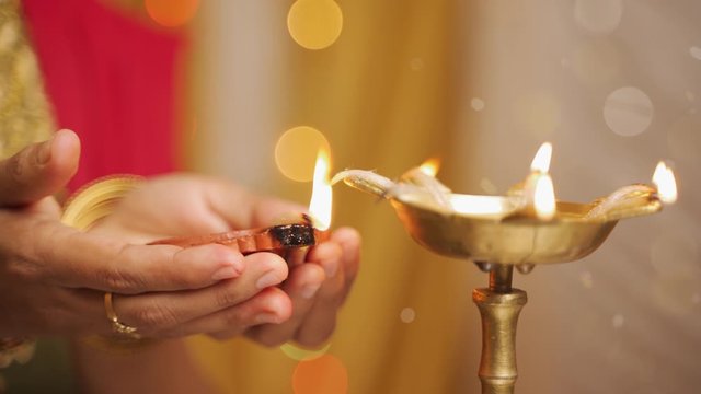 Closeup of woman hands lighting lantern diya or Lamp during festival ceremony - concept of traditional Indian festival and ritual celebrations.