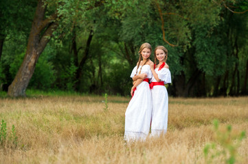 Beautuful Girls with braided hair, white dress and  red ribbons outdoor. Сountry girls. 