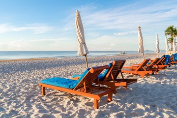 Fototapeta na wymiar Sun loungers chairs and white canvas umbrella with sea view.