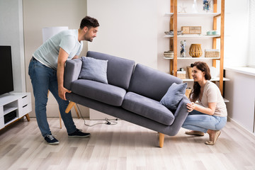 Couple Moving And Carrying Sofa Furniture