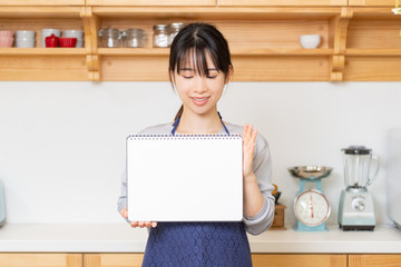キッチンでスケッチブックを持つ若い女性